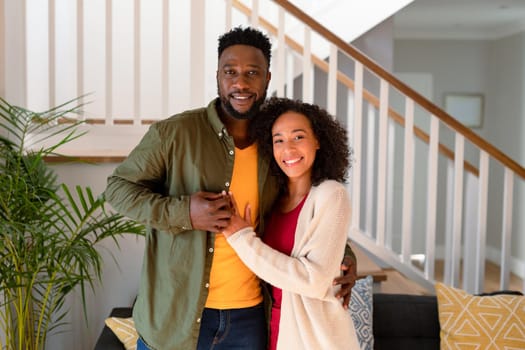 Happy african american couple hugging and looking at camera. family time, leisure and spending time at home.