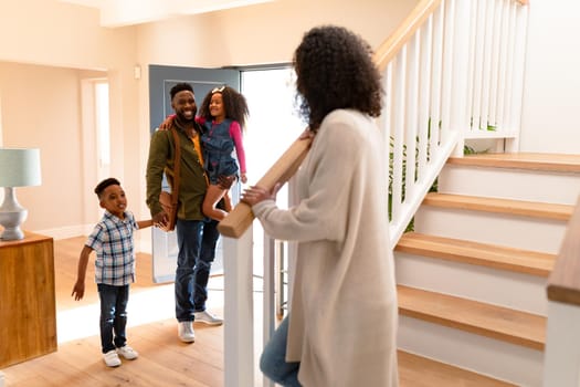 Happy african american family welcoming father coming back home. family time, having fun together at home.