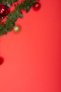 Composition of garland with baubles and copy space on red background. christmas, tradition and celebration concept.