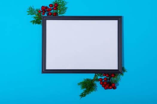 Composition of white card in frame with copy space and tree branches on blue background. christmas, tradition and celebration concept.