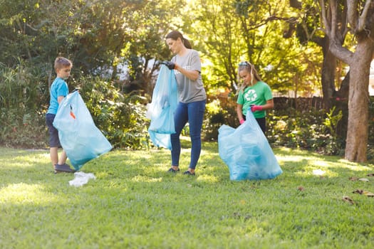 Caucasian mother, son and daughter putting rubbish in refuse sacks in the countryside. eco conservation volunteers, countryside clean-up.