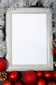 Composition of white card in frame with copy space and christmas decorations on black background. christmas, tradition and celebration concept.