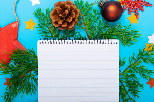 Composition of notebook with copy space and christmas decorations on blue background. christmas, tradition and celebration concept.