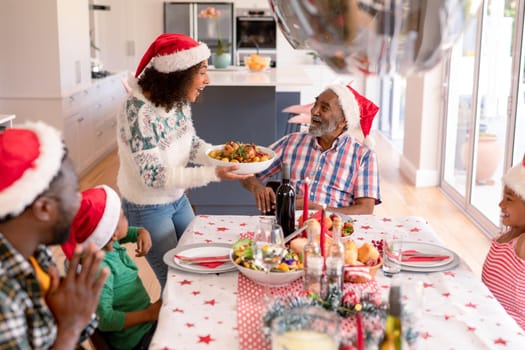 Happy multi generation family wearing santa hats, having christmas meal. family christmas time and festivity together at home.