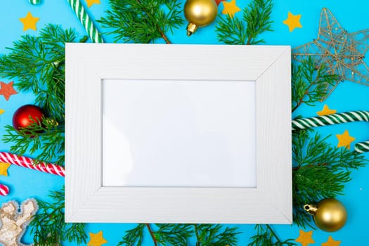 Composition of white card in frame with copy space and christmas decorations on blue background. christmas, tradition and celebration concept.