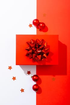 Composition of red christmas present with baubles on white and red background. christmas, tradition and celebration concept.