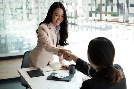 Young business asian people shaking hands in the office. Finishing successful meeting