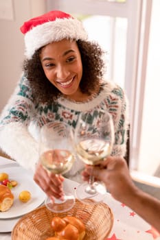 Happy african american woman making toast at christmas table. family christmas time and festivity together at home.