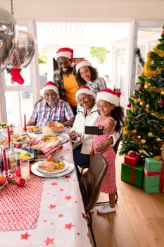 Happy multi generation family wearing santa hats, taking selfie. family christmas time and festivity together at home.