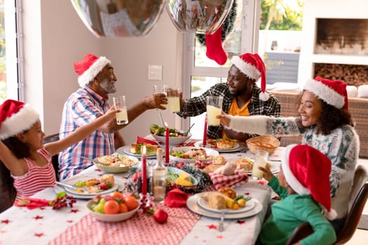 Happy multi generation family wearing santa hats, having christmas meal. family christmas time and festivity together at home.