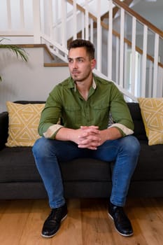 Thoughtful caucasian man sitting on sofa and looking at camera. lifestyle, leisure and spending free time at home.