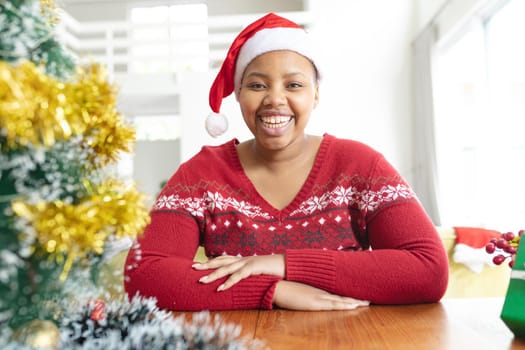 Happy african american plus size woman in santa hat making christmas video call on laptop. christmas, festivity and communication technology.