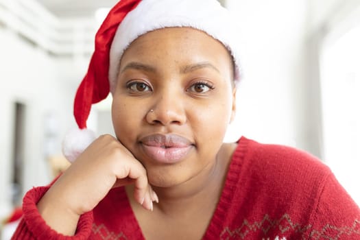 Happy african american plus size woman in santa hat making christmas video call on laptop. christmas, festivity and communication technology.