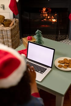 Back view of african american woman using laptop with copy space on screen. christmas, festivity and communication technology.