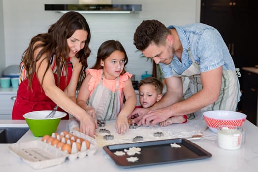 Happy caucasian family baking together, making cookies in kitchen. family time, having fun together at home.