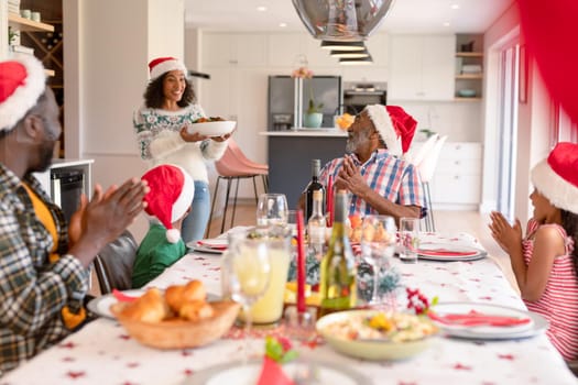 Happy multi generation family wearing santa hats, having christmas meal. family christmas time and festivity together at home.