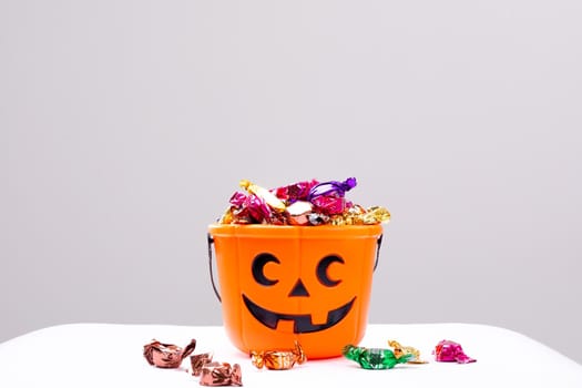 Composition of halloween bucket with trick or treat sweets on white background. halloween tradition and celebration concept.