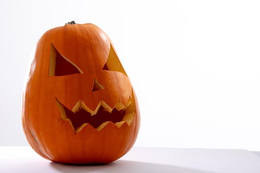 Composition of scary halloween carved orange pumpkin on white background. halloween tradition and celebration concept.