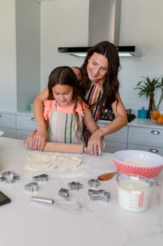 Happy caucasian mother and daughter baking together, making cookies in kitchen. family time, having fun together at home.