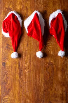 Composition of santa claus hats and copy space on wooden background. christmas, tradition and celebration concept.