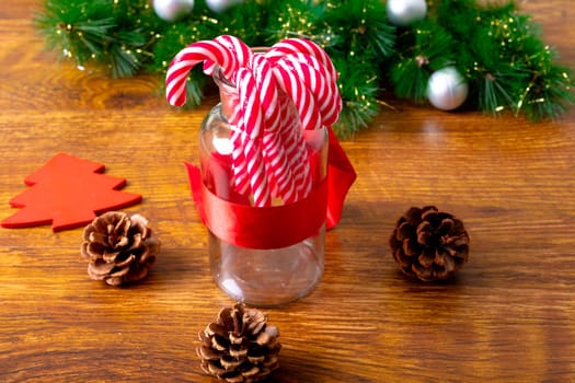 Composition of christmas decorations with candy canes, pine cones and garland on wooden background. christmas, tradition and celebration concept.