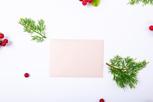 Composition of white card with copy space and branches with berries on white background. christmas, tradition and celebration concept.