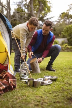 Caucasian father and son setting up a tent together in the garden. fatherhood and love concept