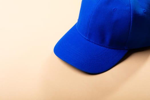 Composition of traditional peaked blue baseball cap on pale brown background. fashion and accessories concept.