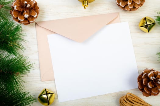 Composition of white card with copy space, envelope and christmas decorations on wooden background. christmas, communication, tradition and celebration concept.