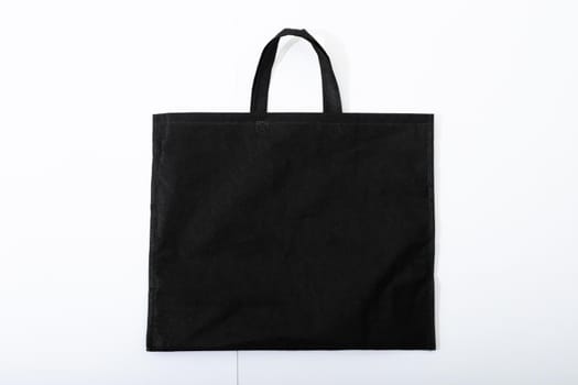 Composition of empty black canvas shopping bag lying flat on white background. shopping and retail concept.