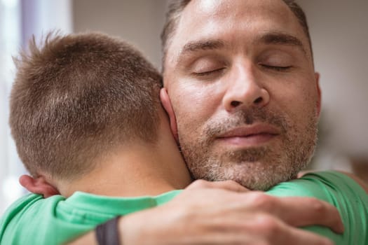 Close up view of caucasian father hugging his son at home. fatherhood and love concept