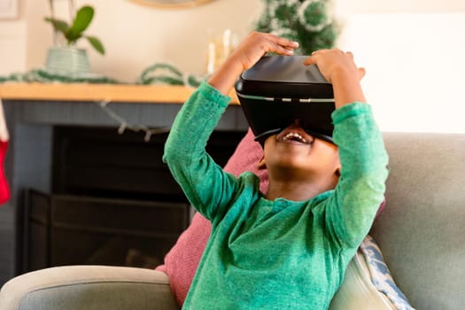 African american boy wearing vr headset and having fun at home. childhood, leisure and discovery using technology at home.