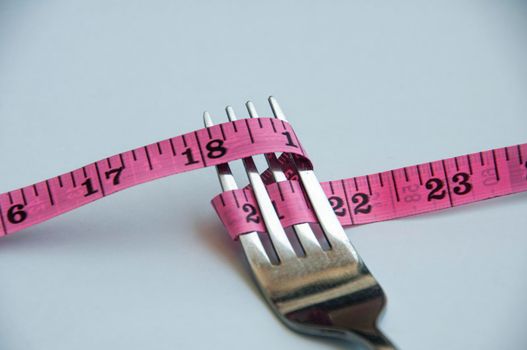 Fork tied with measuring tape. Weight loss and fitness concept
