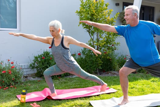 Happy caucasian senior couple practicing yoga together in garden. active and healthy retirement lifestyle at home and garden.