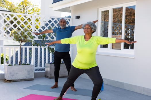 Focused african american senior couple practicing yoga in garden. active and healthy retirement lifestyle at home.