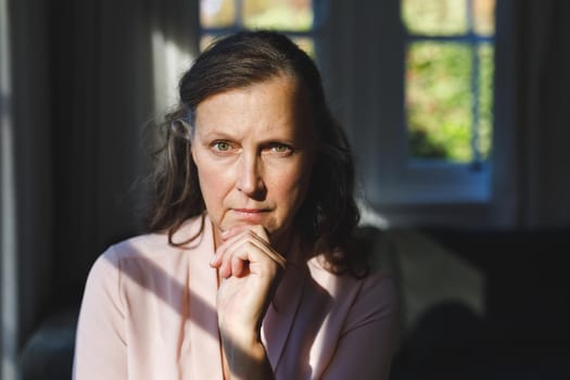 Portrait of thoughtful senior caucasian woman in bedroom, looking to camera. retirement lifestyle, spending time alone at home.