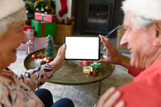 Caucasian senior couple wearing santa hats using tablet with copy space at christmas time. christmas, festivity and communication technology.