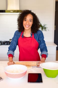 Portrait of happy african american woman wearing apron, baking in kitchen. cooking and baking, spending time at home.