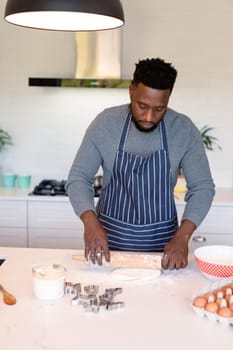 Focused african american man wearing apron, baking in kitchen. cooking and baking, spending time at home.