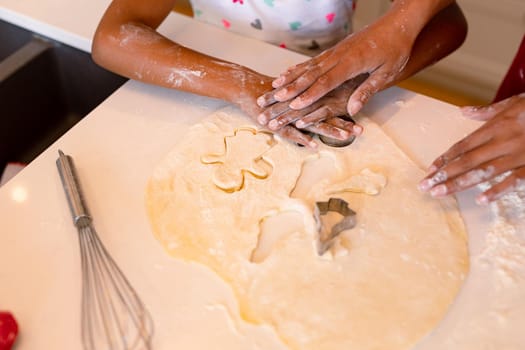Hands of african american mother and daughter baking together in kitchen. family time, having fun together at home.