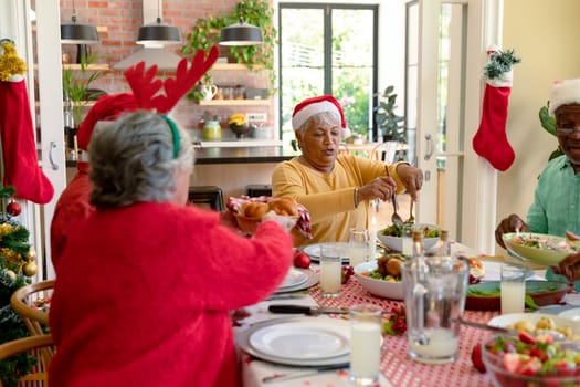 Diverse group of happy senior friends in holiday hats celebrating christmas together at home. christmas festivities, celebrating at home with friends.