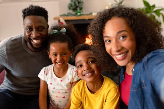 Happy african american family sitting on sofa, taking selfie. family christmas time and festivity together at home.