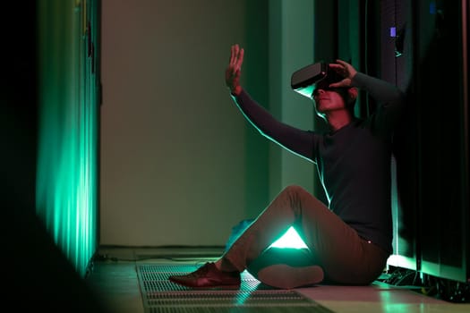 Asian man wearing vr headset while sitting in computer server room. database server and futuristic technology concept