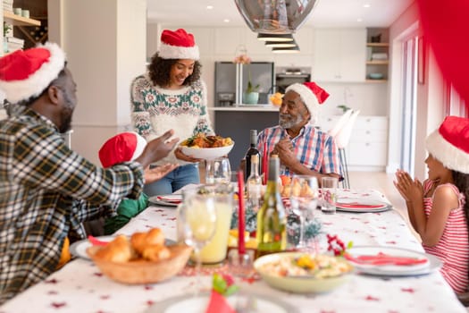 Happy multi generation family wearing santa hats, having christmas meal. family christmas time and festivity together at home.