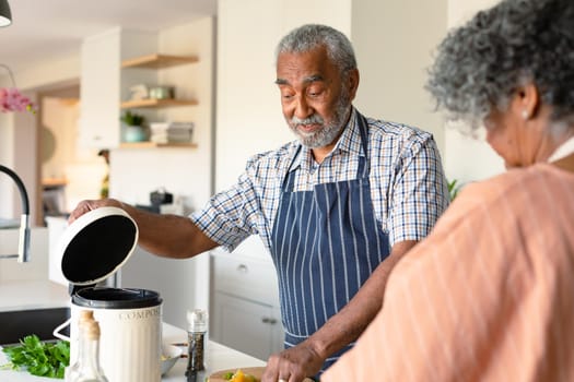 Happy arfican american senior couple preparing meal together and using laptop. healthy retirement lifestyle at home.