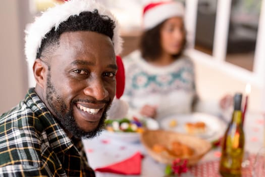 Happy african american man looking at camera at christmas table. family christmas time and festivity together at home.