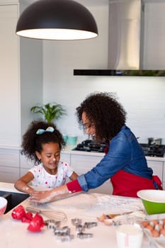 Happy african american mother and daughter baking together in kitchen. family time, having fun together at home.