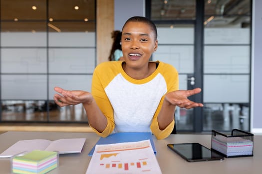 Smiling african american businesswoman in casual gesturing during video conference in office. creative business and office workplace.