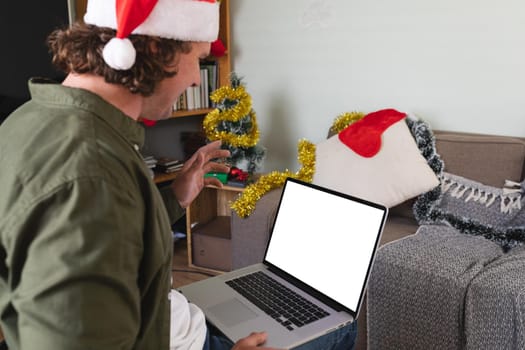 Caucasian disabled man in santa hat using laptop with copy space at home during christmas. christmas festivity and celebration concept