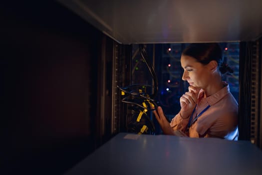 Thoughtful caucasian female engineer inspecting the server in computer server room. database server management and maintenance concept